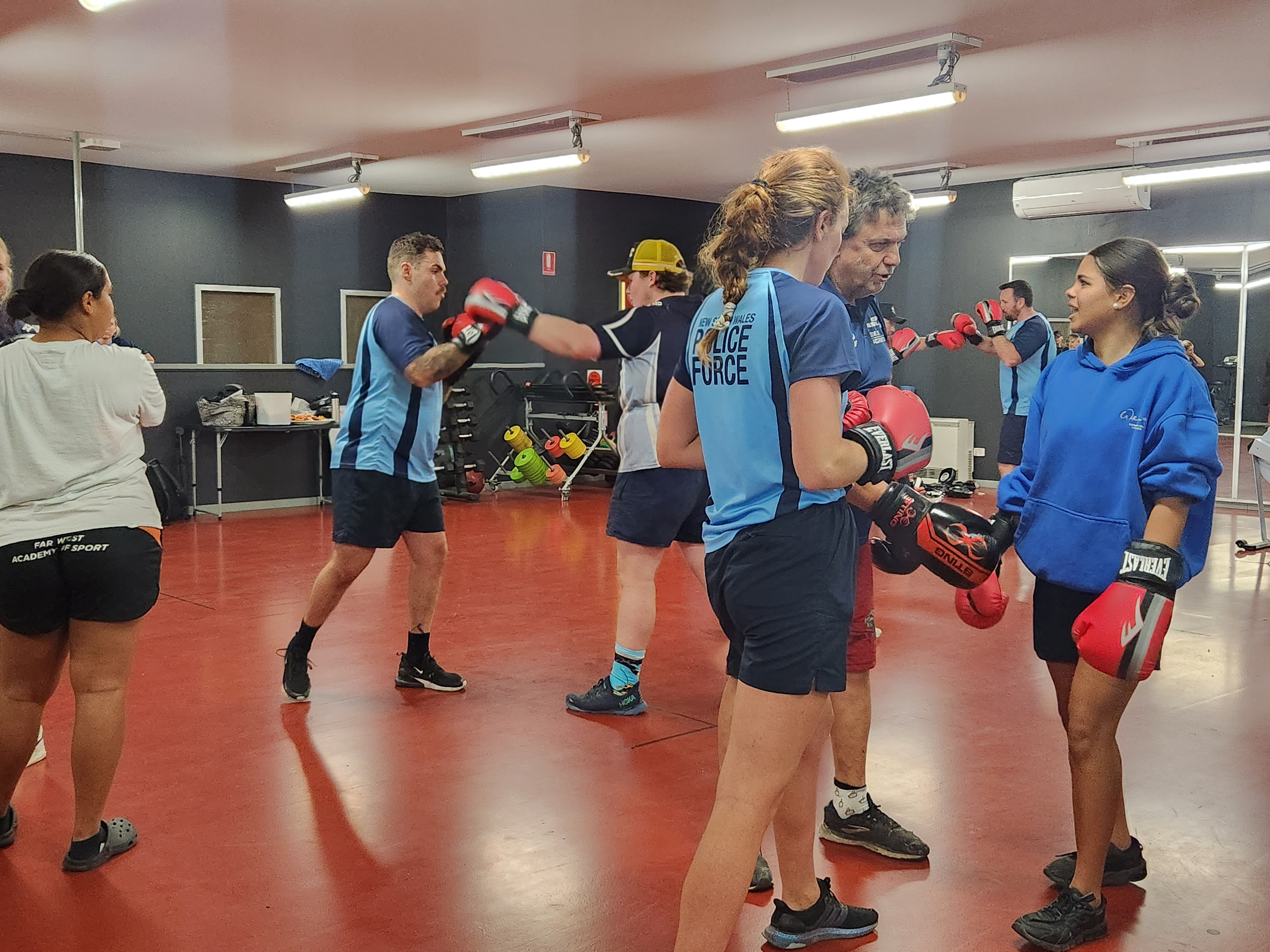 Kids participating in the boxing program with the help of a boxing coach and officers.