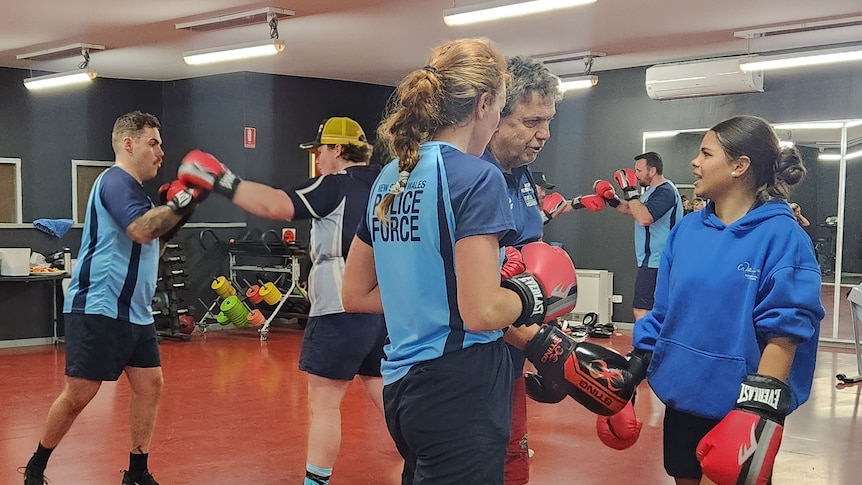 Kids participating in the boxing program with the help of a boxing coach and officers.