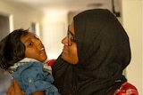 Shizleen Aishath holding her 2-year-old son Kayban Jamshad in her arms.