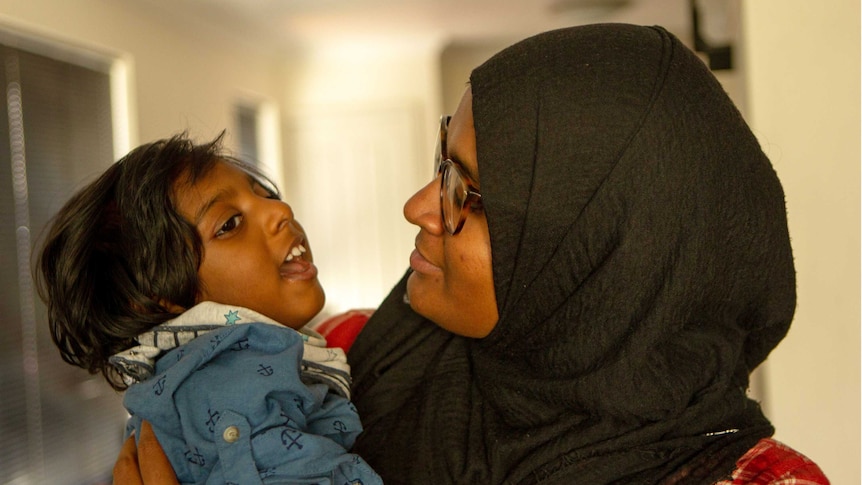 Shizleen Aishath holding her 2-year-old son Kayban Jamshad in her arms.