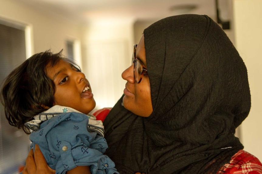 Shizleen Aishath holding her 2-year-old son Kayban Jamshad in her arms.