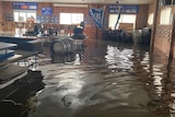 A flooded club room with tables and kegs floating in the water.