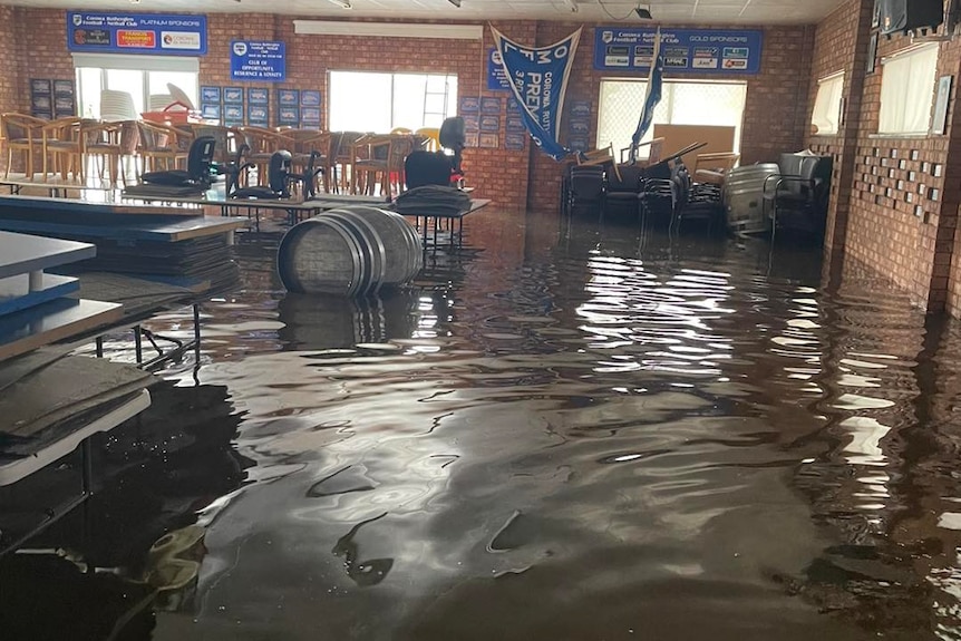 A flooded club room with tables and kegs floating in the water