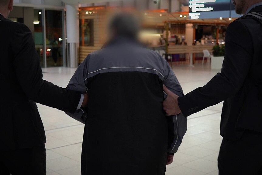 A man being escorted to a shopping area