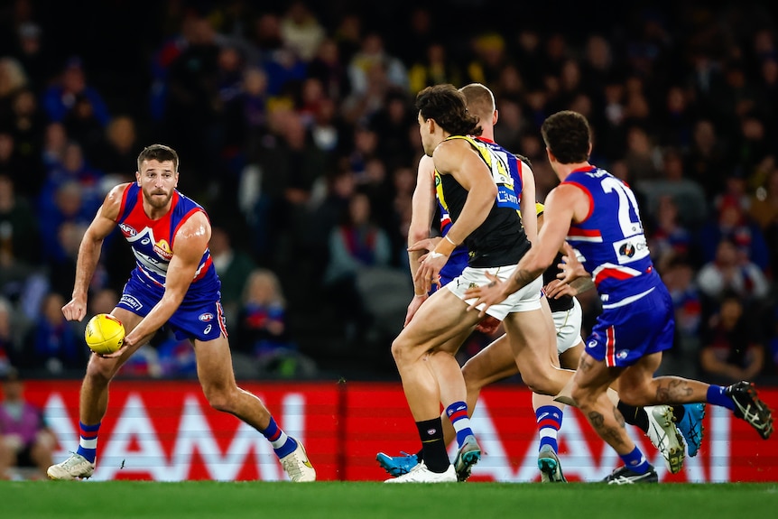 Western Bulldogs' Marcus Bontempelli gets ready to handball to a teammate as an opposition player tries to close him down.. 