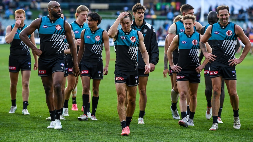 Port Adelaide AFL players walk off Adelaide Oval after loss to Brisbane Lions.