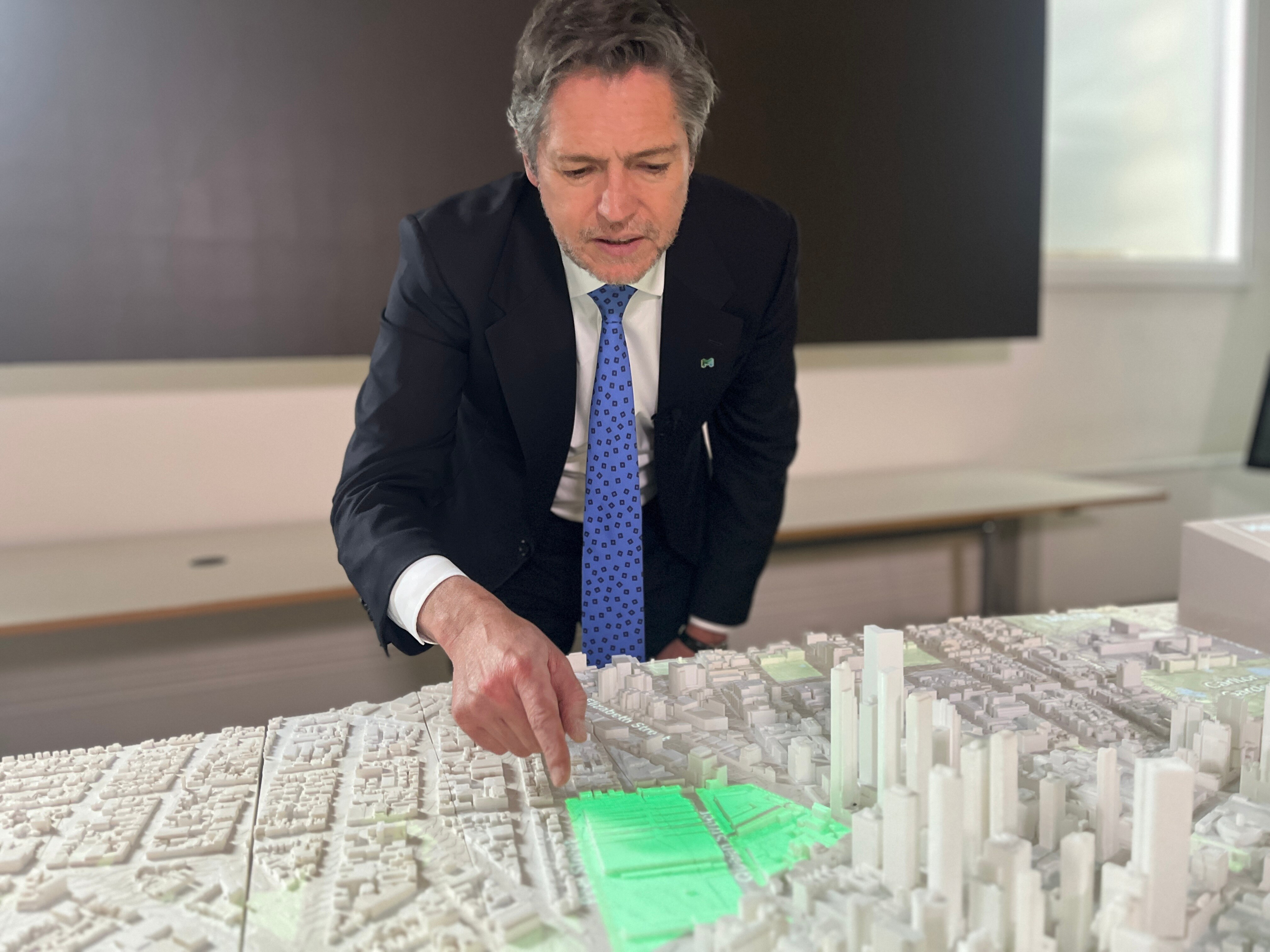 A man in a suit pointing to a 3D model of the Queen Victoria Market and Melbourne CBD.