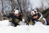 Two Norwegian army members in snow camouflage aim their weapons.