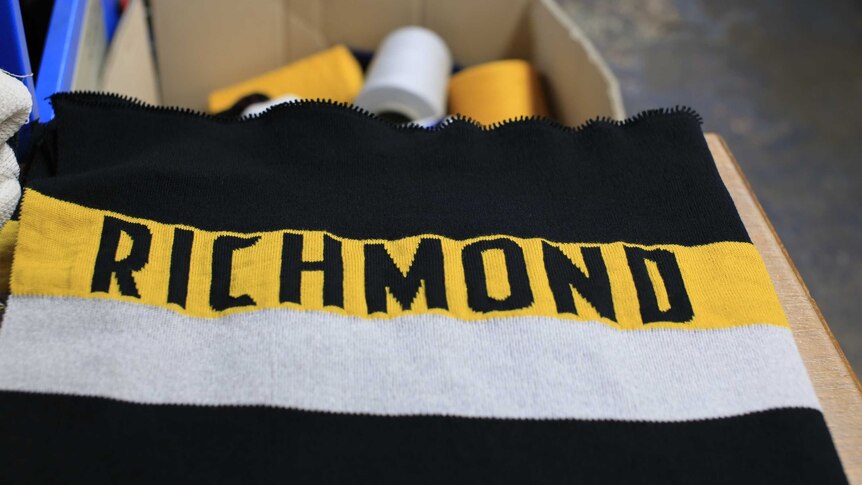 A close-up photo of a Richmond scarf with spools of wool in a box in the background.
