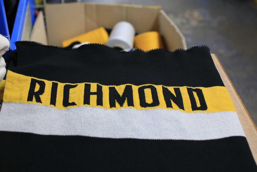 A close-up photo of a Richmond scarf with spools of wool in a box in the background.