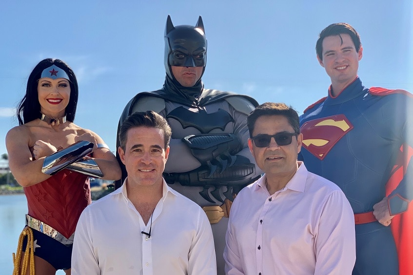 Superheroes stand behind theme park managers