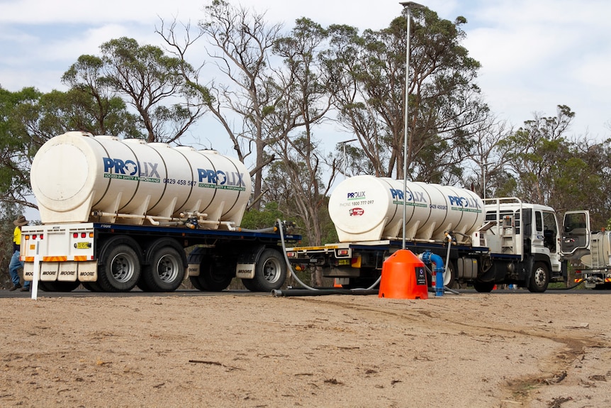 Two water delivery trucks in a rural setting