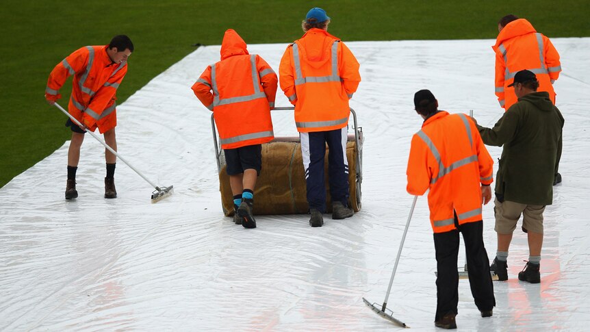 Groundsmen work in vain to protect pitch