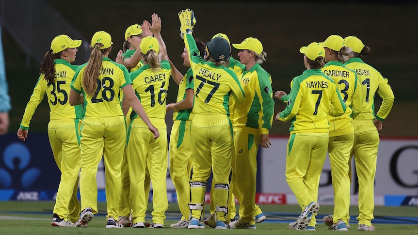 The entire Australian team meet in a group as they celebrate a New Zealand wicket.