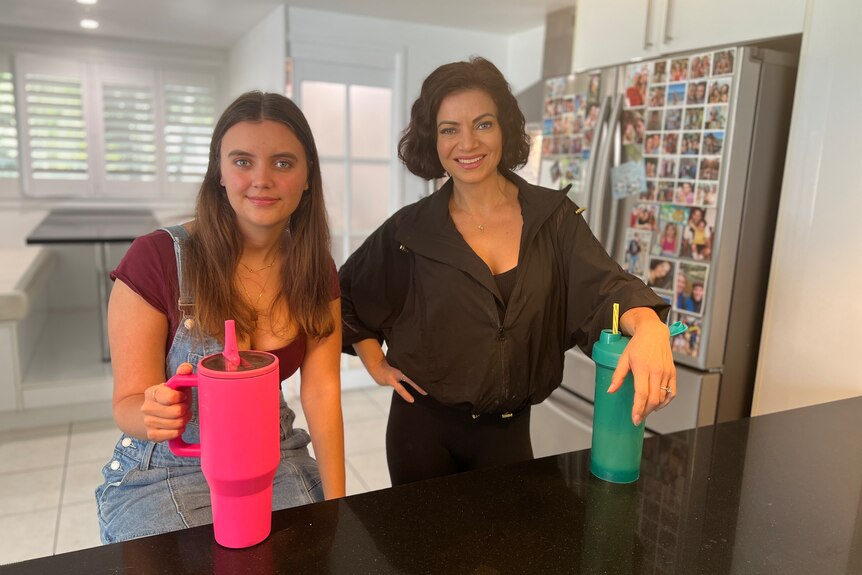 a woman and her daughter standing smiling together