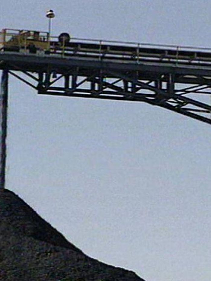 Coal falling from a mine conveyor belt.