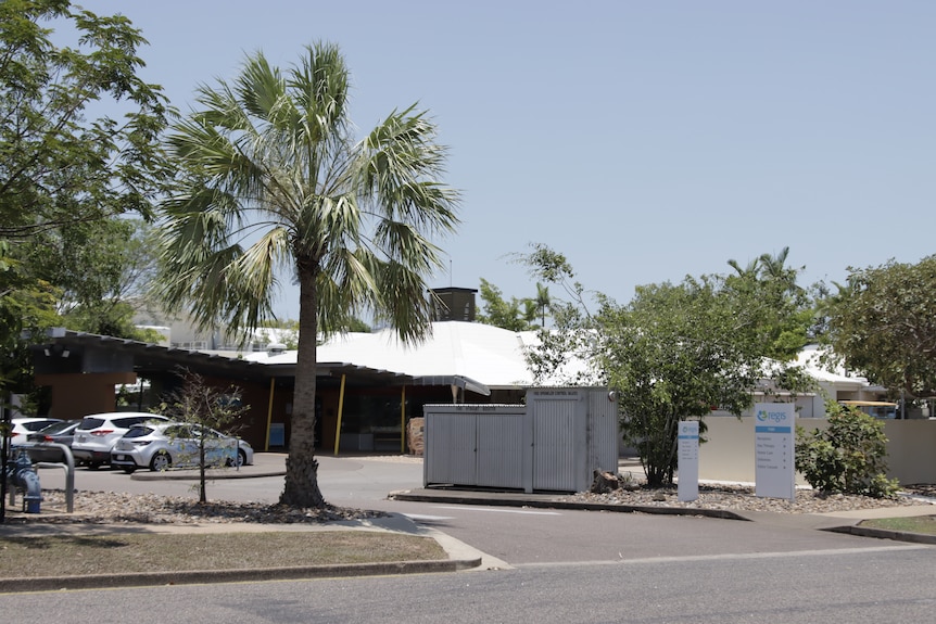 Cars are parked in front of the Regis Tiwi Gardens aged care facility in Darwin, which has trees out the front. 