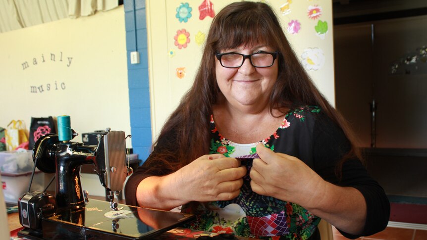 woman smiling behind old sewing machine
