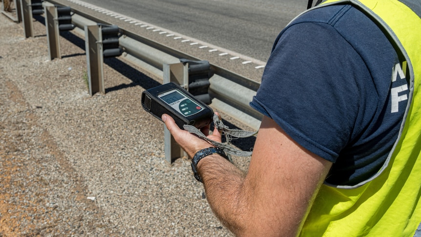 A person holds a hand-held device to detect radioactivity.