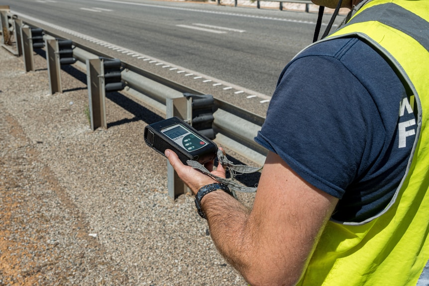 A person holds a hand-held device to detect radioactivity.