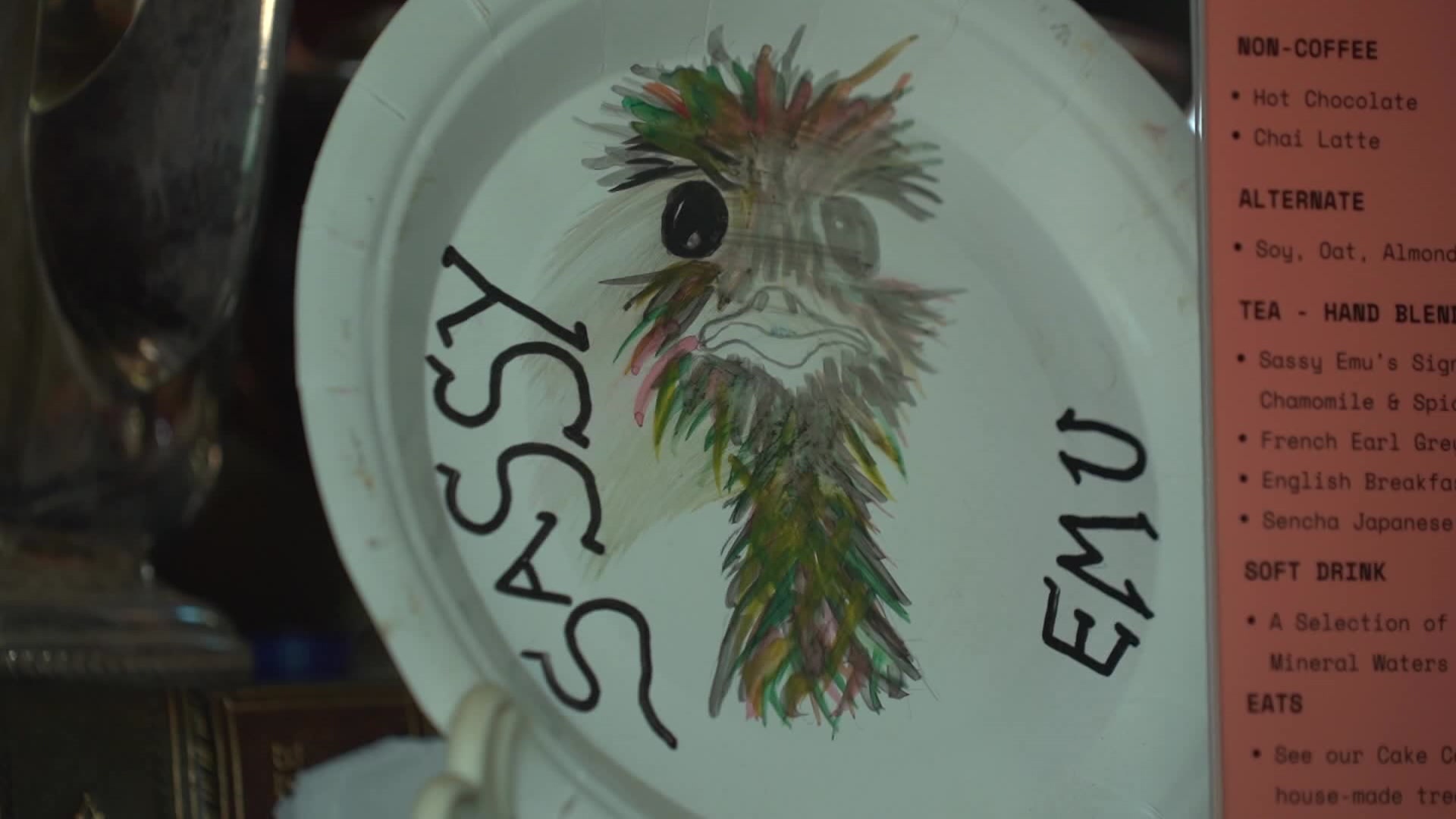 A painting of an emu head on a plate with the letters 'Sassy Emu'. 