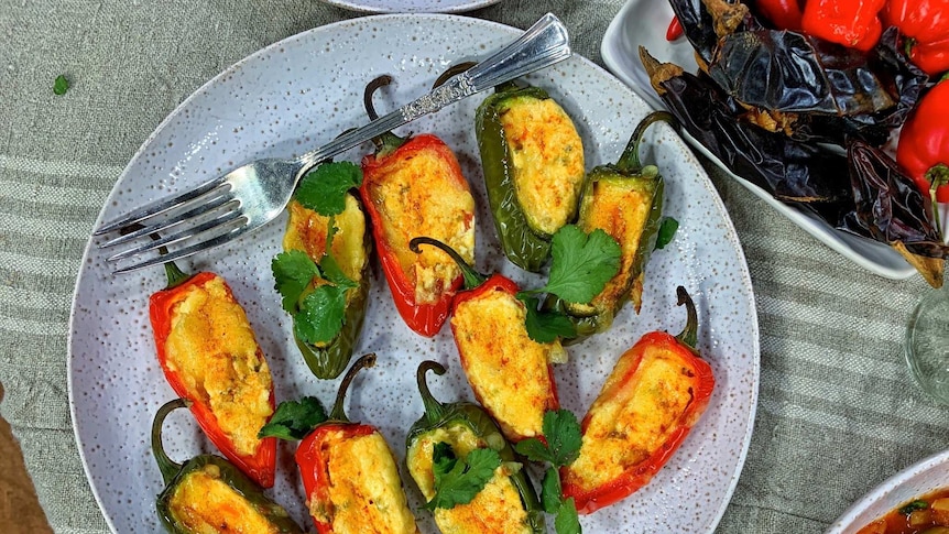 Jalapeno poppers on a plate with fork and two other chilli-based dishes partly visible at bottom.