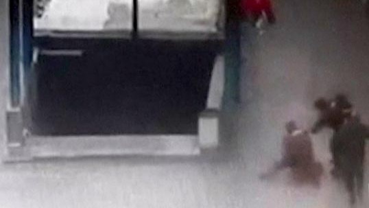 Grainy still from CCTV footage of Russian police arresting a nanny on a street next to subway station stairs.