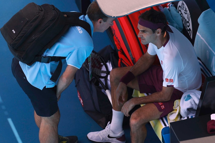 Roger Federer speaks to a trainer about an injury during his Australian Open quarter-final against Tennys Sandgren.
