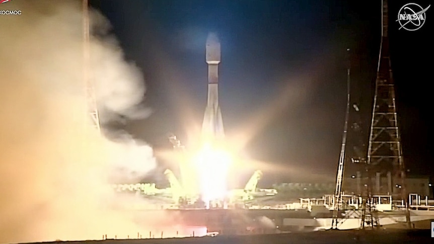 A rocket blasts off at night, sending engine exhust over the launch pad.