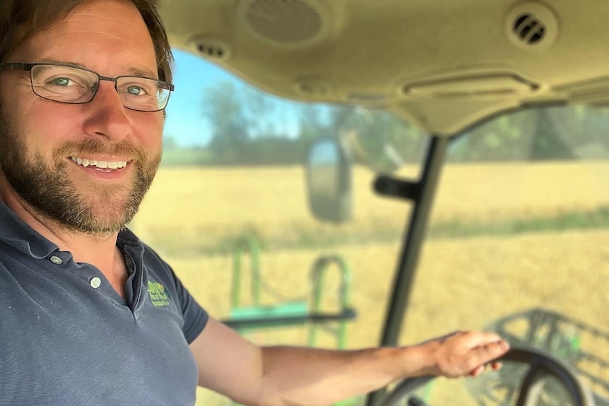 A man looks at the camera while sitting in the cab of a harvester
