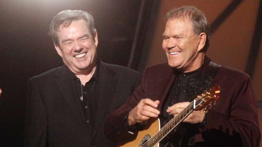 Singer Glen Campbell strums a guitar during his tribute as singer Brad Paisley (L) and composer Jimmy Webb look on at the 45th Country Music Association Awards in Nashville, Tennessee, November 9, 2011.