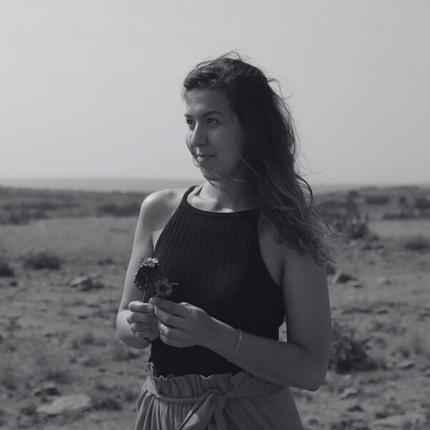 Anna-Zoë Herr stands holding a flower