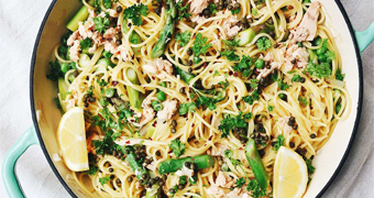 A pan of one pot spaghetti with parsley, capers, tuna, lemon, peas and asparagus.