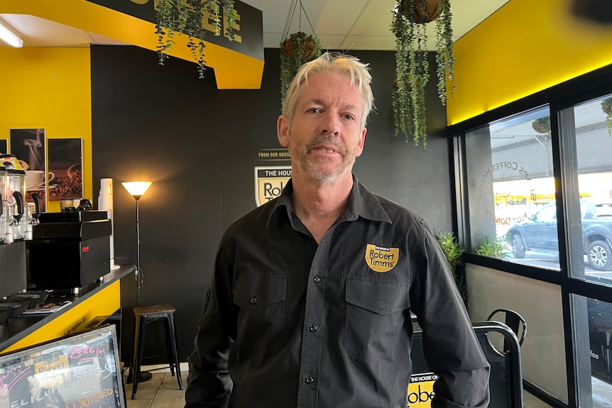 Man inside a cafe looking at the camera smiling.