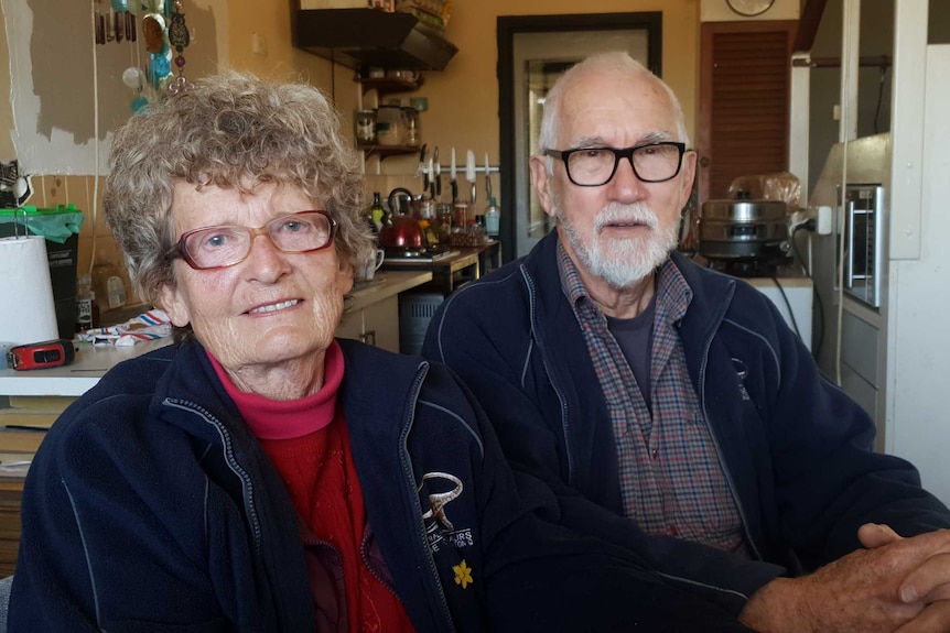 An elderly couple sitting in a kitchen