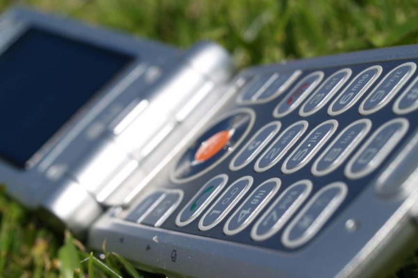 A hand holds a mobile phone as it writes a text message