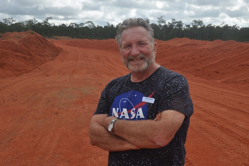A NASA scientists smiles standing on the red dirt of a remote launch site in north-east Arnhem Land.