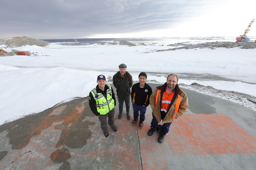 Four men in warm clothing with snow in the background