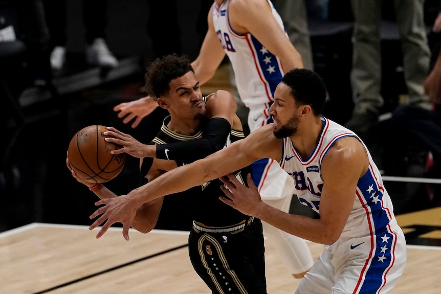 Ben Simmons reaches out to try and block or steal the ball from Atlanta's Trae Young in the NBA playoffs.