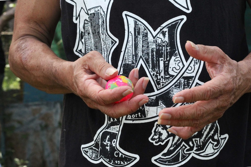 A man's hands hold a pink ball.