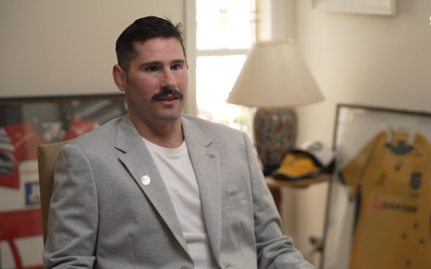 Man in a suit jacket, sitting, being interviewed