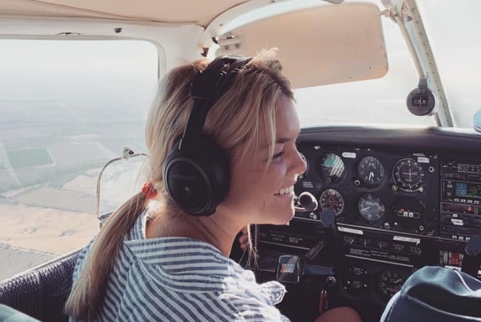 Lucy Samuels smiling at a co-pilot in the cockpit of a plane.