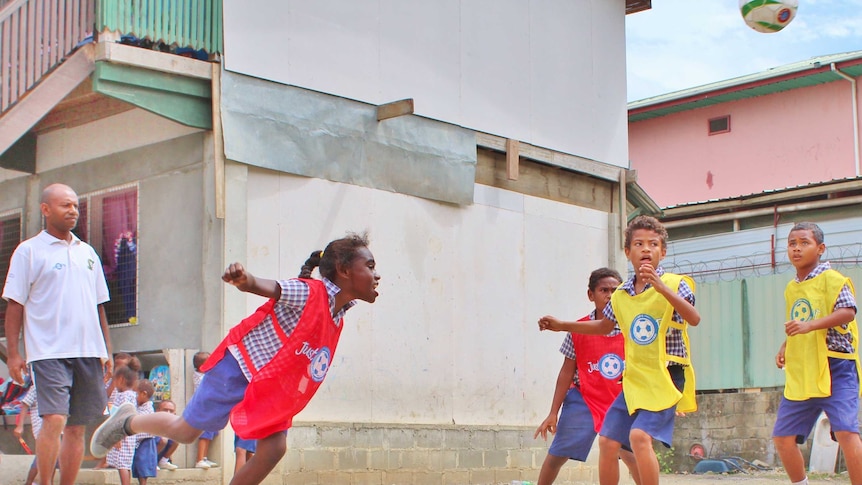 A girl heads the ball in street soccer