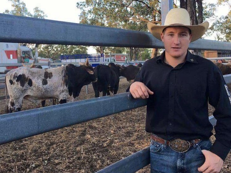 Man stands in front of pen holding rodeo bulls