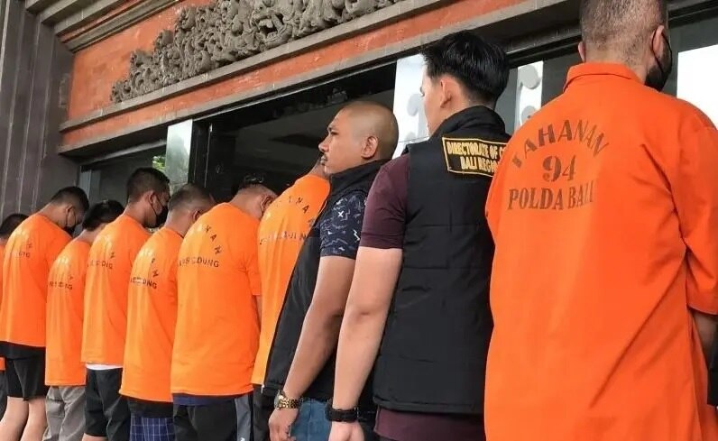 Several men wearing orange t-shirt standing and turning away from the camera