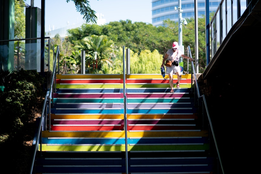 A woman wearing a mask walks down a brightly painted street.