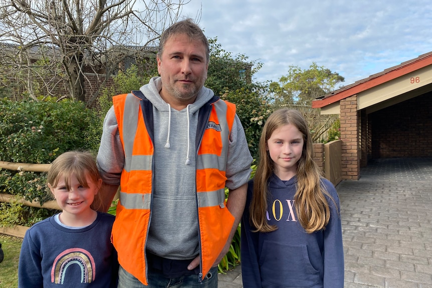 A man wearing a high-vis vest, and two kids.
