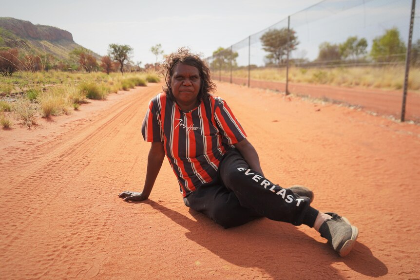 A woman sits in the red dirt