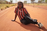 A woman sits in the red dirt
