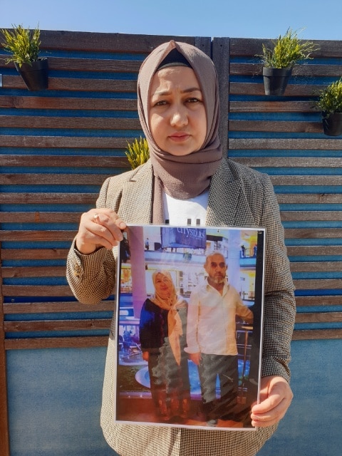 A woman in a headscarf holds a picture of her parents.